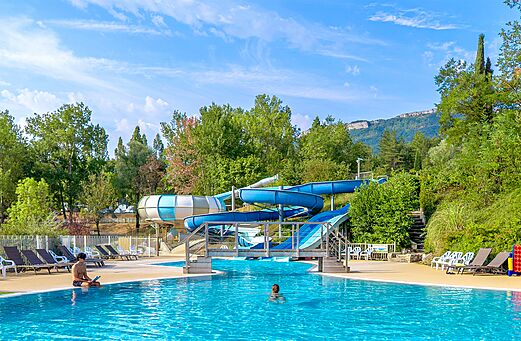 Buitenzwembad met waterglijbanen en stoelen op camping CLICOCHIC Couriou in Recoubeau-Jansac.