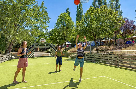 Jongeren basketballen op het multisportterrein van camping CLICOCHIC Couriou in Recoubeau-Jansac.