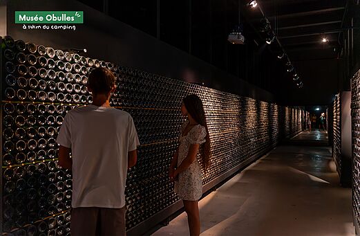 Interieur Musée Obulles, flessenmuren, bezoekers. Toeristische plek om te ontdekken.