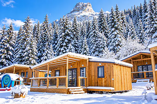 Houten stacaravans besneeuwd, bos en berg op camping CLICOCHIC Alpes Lodges. Houten stacaravans besneeuwd, bos en berg op camping CLICOCHIC Alpes Lodges.