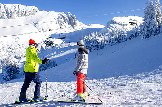 Skiërs op besneeuwde piste, skilift, bergen bij camping CLICOCHIC Alpes Lodges. Skiërs op besneeuwde piste, skilift, bergen bij camping CLICOCHIC Alpes Lodges.