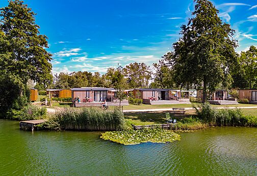 Moderne stacaravans aan een groen meer op camping CAPFUN De Rotonde in Enspijk.