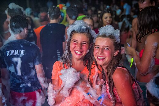 Twee lachende meisjes genieten van een schuimparty op camping CAPFUN De Rotonde in Enspijk.