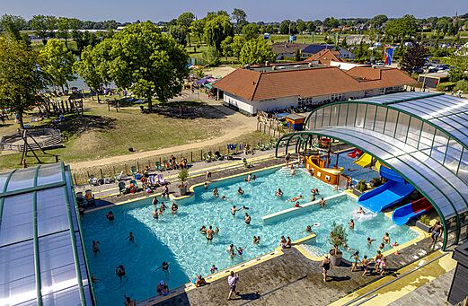 Overdekt buitenzwembad met glijbanen en waterspellen op camping CAPFUN De Rotonde in Enspijk.